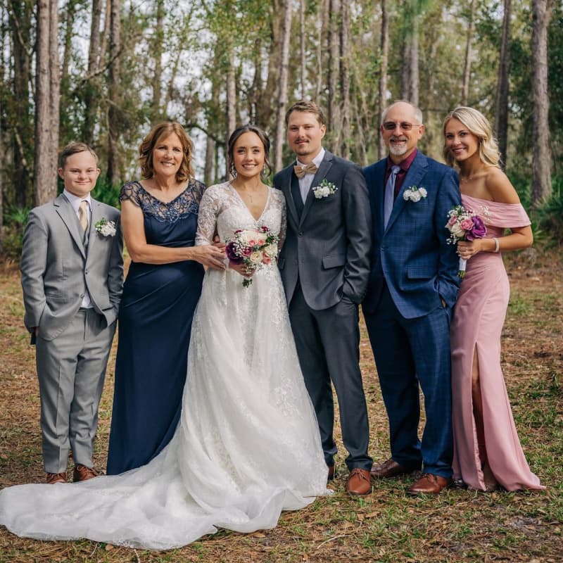 The Baar family at an outdoor wedding — Joey, parents, siblings together in a Florida pine forest.