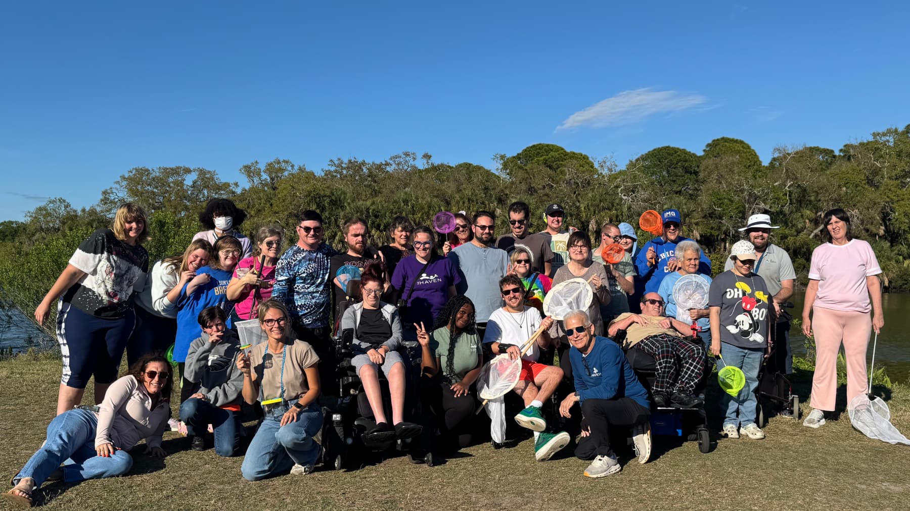 Large Monthly Nature Program group gathered by a Florida preserve waterfront with butterfly nets on a bright sunny day.