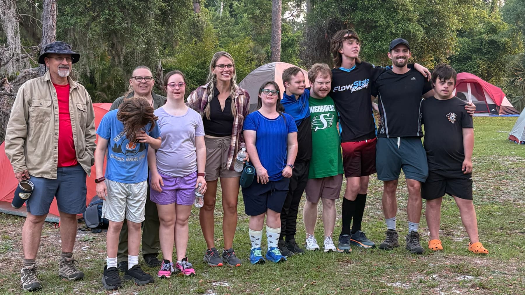 Outdoor Warriors group standing together at a Florida campsite with tents pitched among pines.